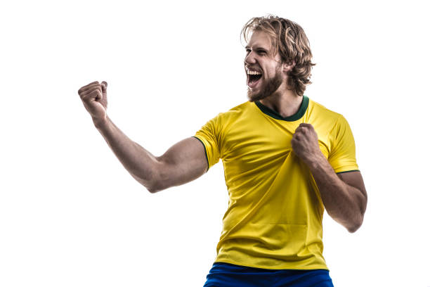 istock Male athlete / fan in yellow uniform celebrating on white background 883205534