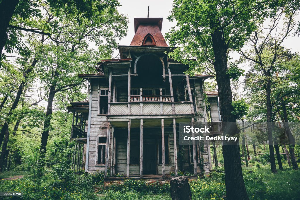 Old creepy wooden abandoned haunted mansion Old creepy wooden abandoned haunted mansion house building among green forest House Stock Photo