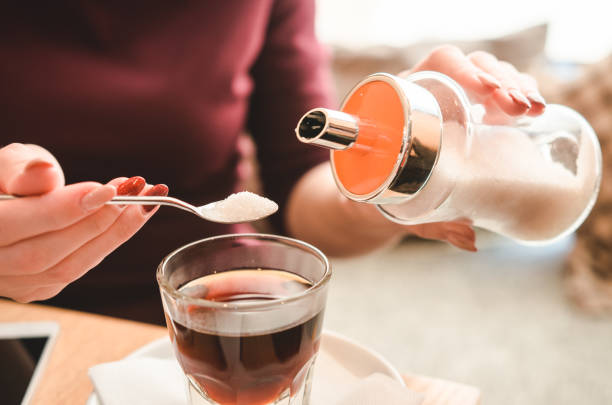 primo piano della signora che versa zucchero al caffè caldo - pouring coffee human hand cup foto e immagini stock