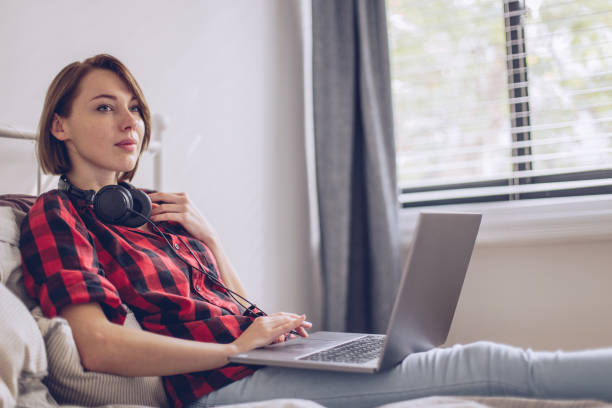 istock Beautiful young woman using her laptop in the bed 883226278