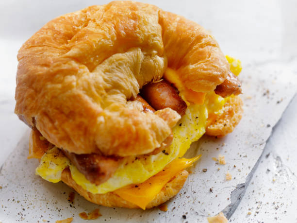 ei, wurst und käse frühstück croissant - cheese focus on foreground on top of portion stock-fotos und bilder