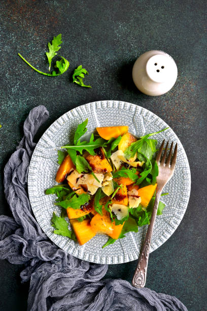 istock Autumn persimmon salad with arugula and parmesan cheese 883276016