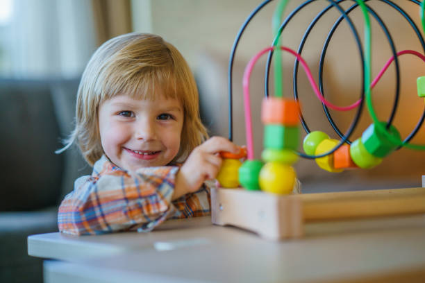 Small cute boy looking at camera and playing with abacus