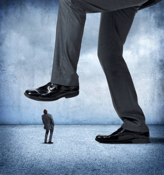 istock Large Businessman About To Step On Small Businessman 883283604