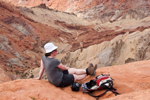 Sitting on the Edge of the Crater Canyonlands National Park, Utah, USA - May 17, 2012: Upheaval Dome is an impact crater formed when a meteor struck the area. The crater is located in the Island in the Sky section of the park. This woman hiker is sitting on the crater rim. jeff goulden canyonlands national park stock pictures, royalty-free photos & images