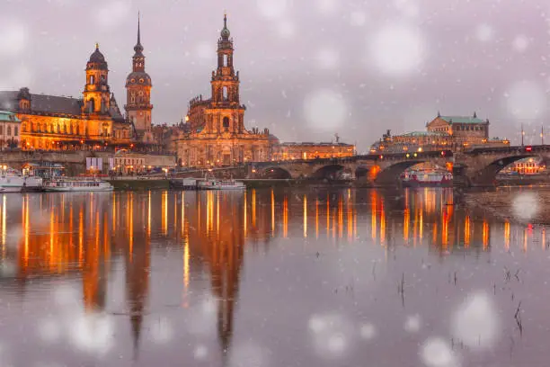 Dresden Cathedral of the Holy Trinity or Hofkirche, Bruehl's Terrace or The Balcony of Europe, Semperoper and Augustus Bridge with reflections in the river Elbe at snowy christmas night in Dresden, Saxony, Germany