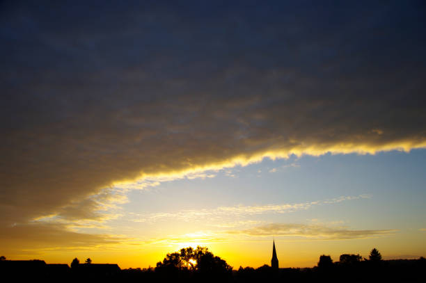 Sunrise over the village with church tower in silhouette