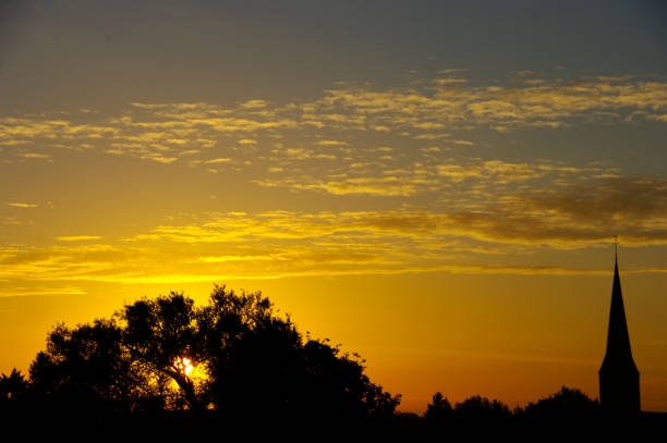 Sunrise over the village with church tower in silhouette