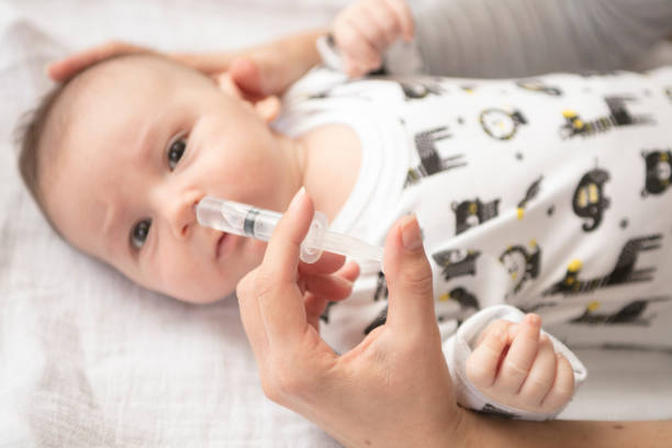 istock Mother cleans the baby's nose with a syringe 883321836