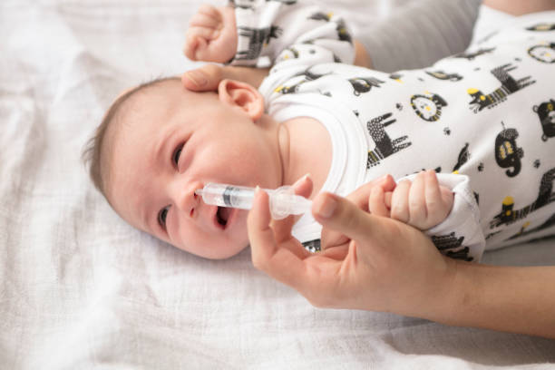 istock Mother cleans the baby's nose with a syringe 883322200
