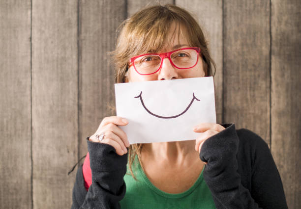 madura mediados mujer de edad con una sonrisa pintada en papel - smiley face smiling sign people fotografías e imágenes de stock