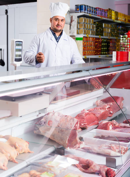 istock Man seller at the counter with meat 883384160