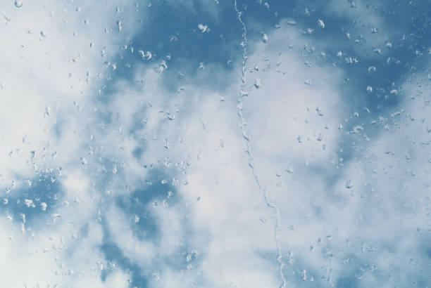 istock Water drops on a window glass, a blue cloudy sky at the background. 883386274