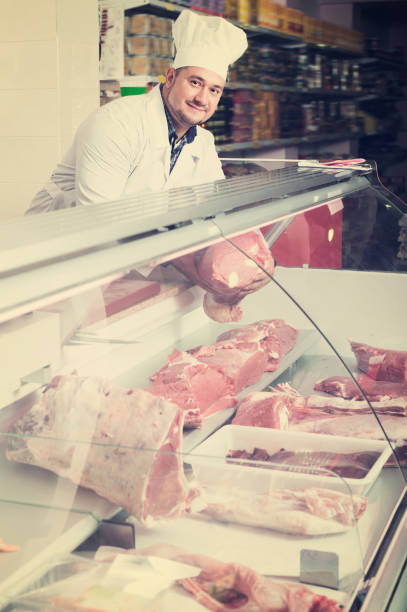 istock Happy salesman near display with cooled meat 883386538