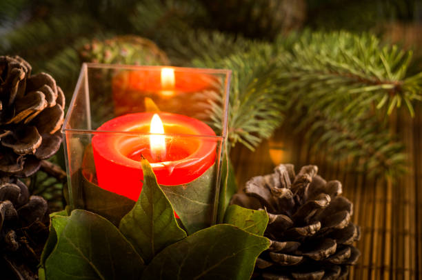 istock christmas candle in plastic cup with pine tree cones 883429780