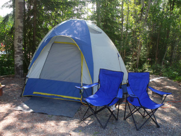 istock Gray and blue dome camping tent with two blue chairs on campsite 883532782