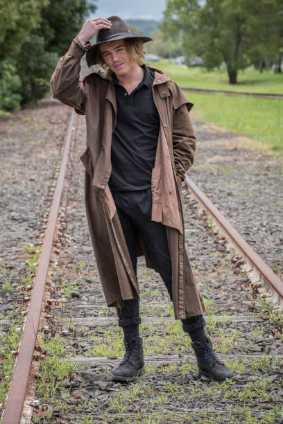 istock Young man in Australian traditional bush gear stands between rail tracks, 883534270