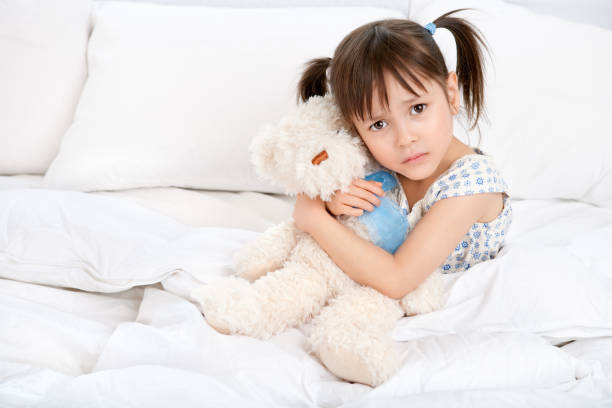 istock Confused girl hugging teddybear on bed 883574108