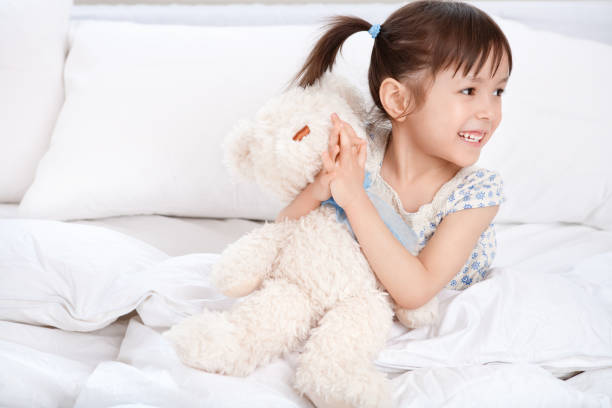 istock Girl hugging teddybear on bed 883574610