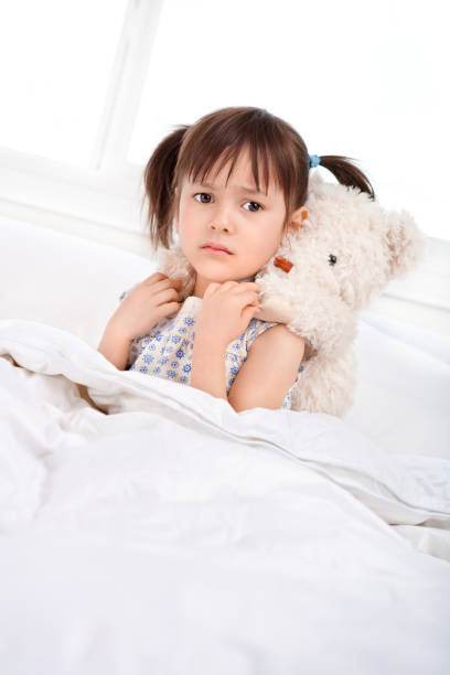istock Sad girl piggy back teddy bear in bed 883574940