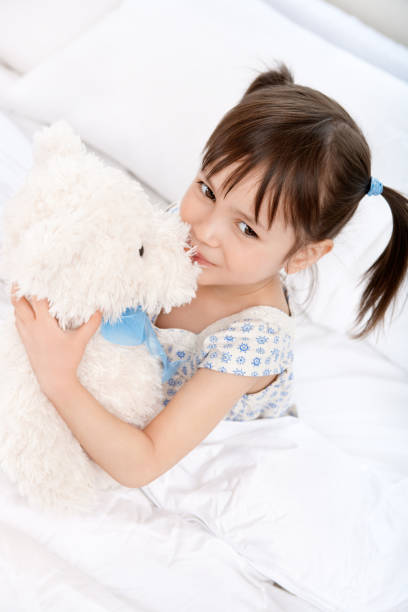 istock Girl kissing teddybear on bed 883578130
