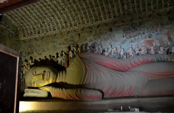 Ancient reclining Buddha statue at the Mogao Caves, an oasis located at a religious and cultural crossroads on the Silk Road, Dunhuang, Gansu province, China. The caves contain some of the finest examples of Buddhist art spanning a period of 1,000 years.