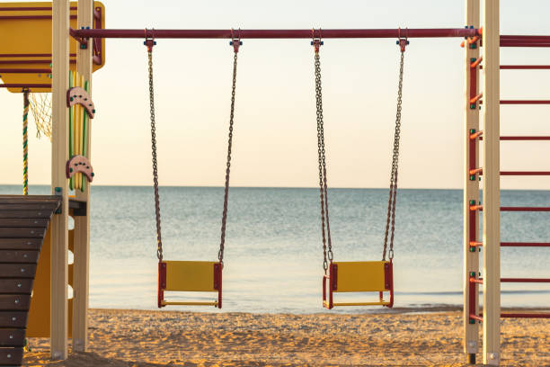 istock Two swings of children's playgrounds on the beach. 883617418