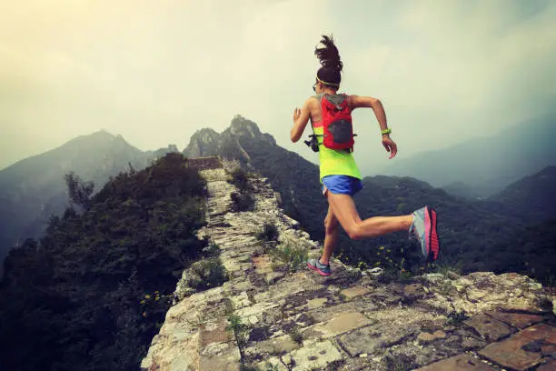 Photo of young woman trail runner running on the great wall