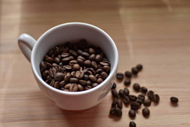 cup full of coffee beans at wooden background/ top view - beverag imagens e fotografias de stock