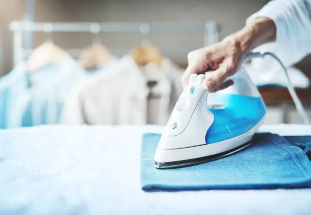 Closeup shot of an unidentifiable woman ironing clothes at home