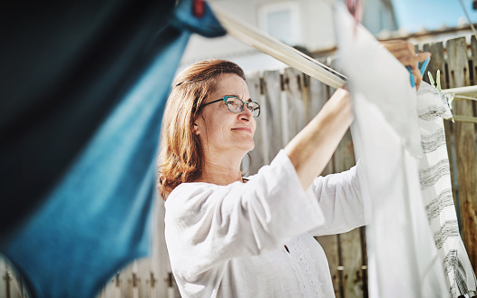 Shot of a mature woman hanging up laundry on a washing line outside
