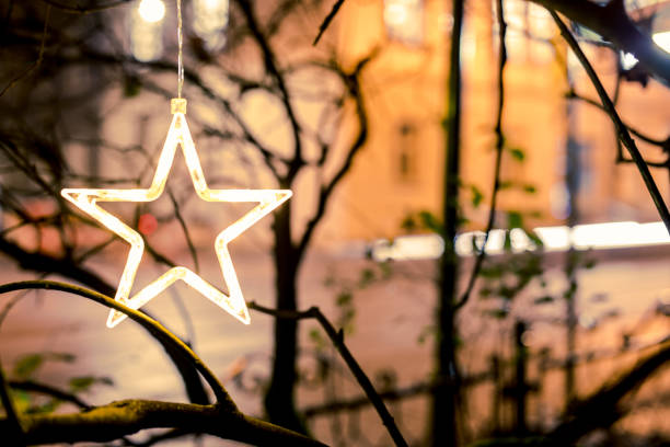 Christmas Neon Star on Tree in Centre of Cracov. Traffic lights in background. Night. Long exposure. Passing car in background. Cracow in Poland.