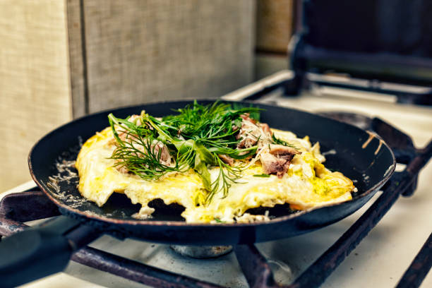 Healthy breakfast. Omelette with bacon and arugula fried in a frying pan