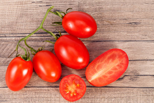 légumes de tomates fraîches, entières et sectionnés, sur planche de bois - sectioned photos et images de collection