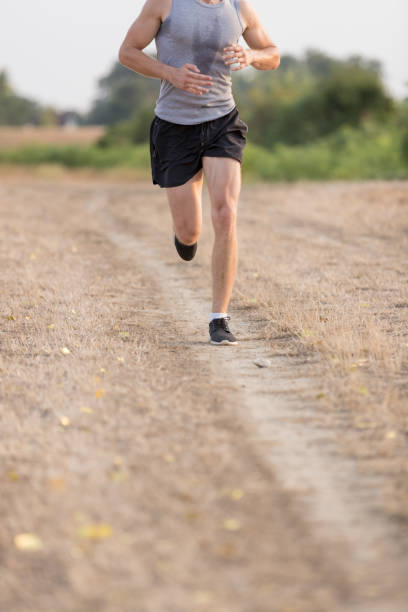 istock Low section of male runner jogging on dirt path 883678958