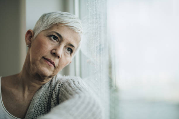 istock Thoughtful mature woman looking through the window. 883695066