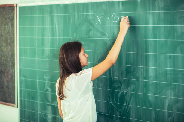 istock Happy schoolchild writing on blackboard. 883706590