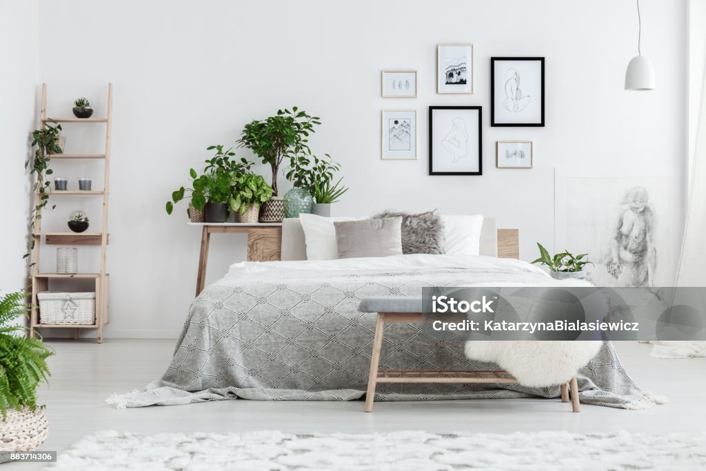 Drawings on the wall Handmade drawings in frames hanging on the wall in white bedroom with potted plants and wooden decorative ladder Bedroom Stock Photo