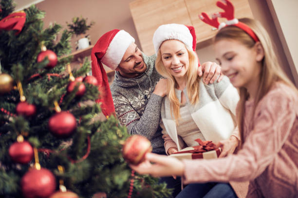 istock Family opening presents by Christmas tree 883725400
