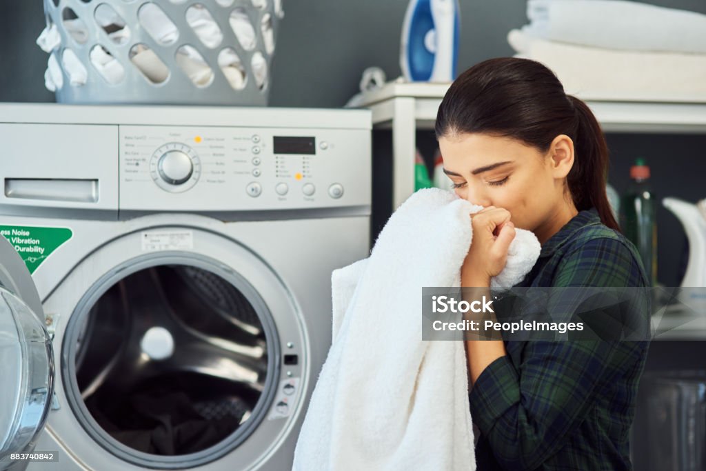 The smell of fresh laundry Cropped shot of an attractive young woman smelling a freshly washed towel while doing laundry at home Laundry Stock Photo