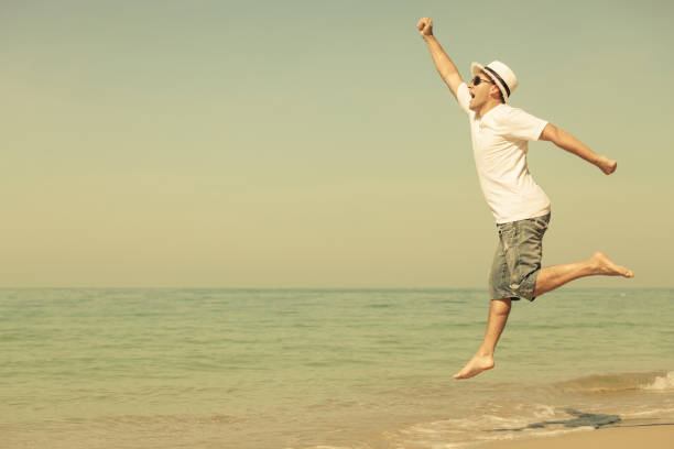 istock Happy man jumping on the beach 883748186