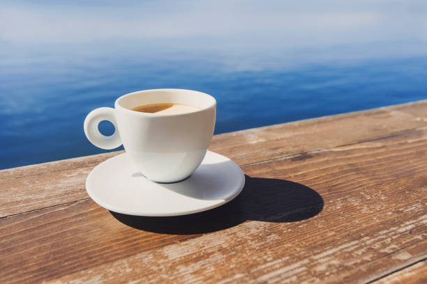 istock Cup of coffee with a sea at the background 883760034