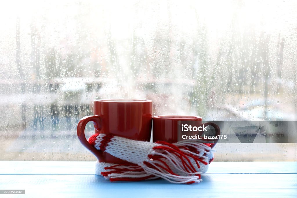 warming gentle hugs hot couple big and small red cup wrapped in a scarf on window background with drops after the rain Coffee - Drink Stock Photo