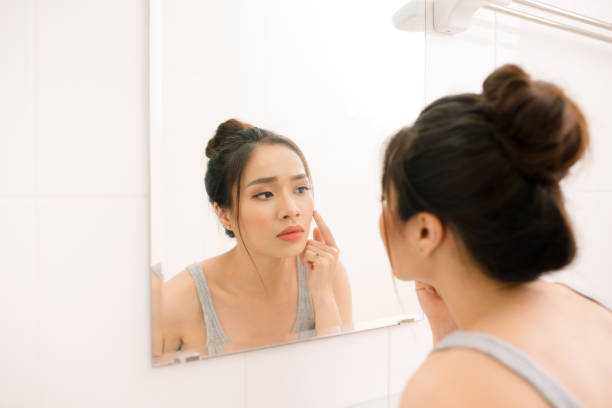 istock Smiling young woman looking to mirror at home bathroom 883805500
