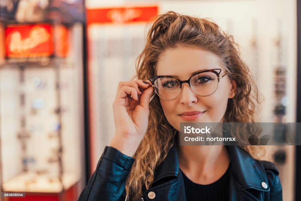 View of a young attractive woman trying glasses at the optician. Eyeglasses Stock Photo