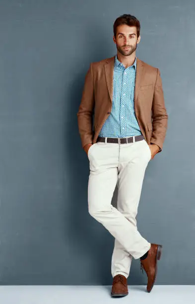 Studio portrait of a stylishly dressed young man posing against a grey background