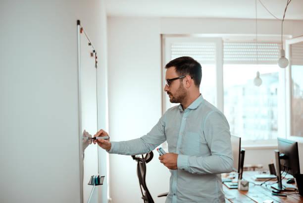istock Profile of handsome man standing and writing on whiteboard. 883810590