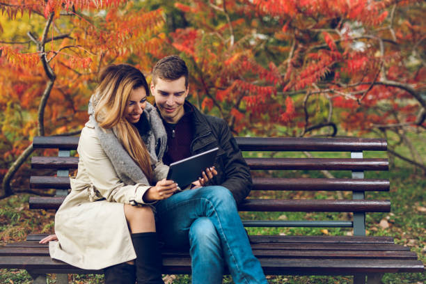 istock Couple using digital tablet in autumn park 883817264