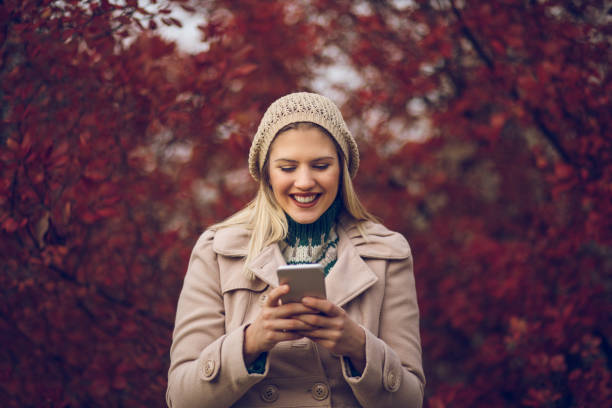 istock Young woman using mobile phone in an autumn park 883817508