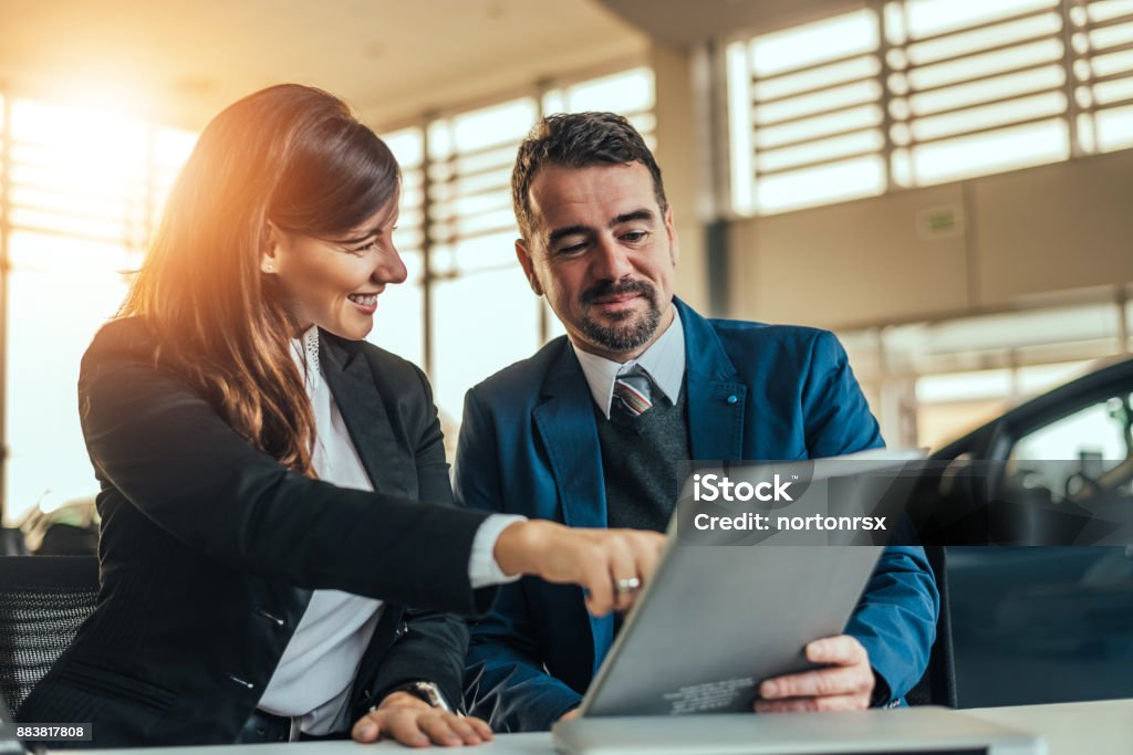 Car dealer showing customer contract. Selling Stock Photo